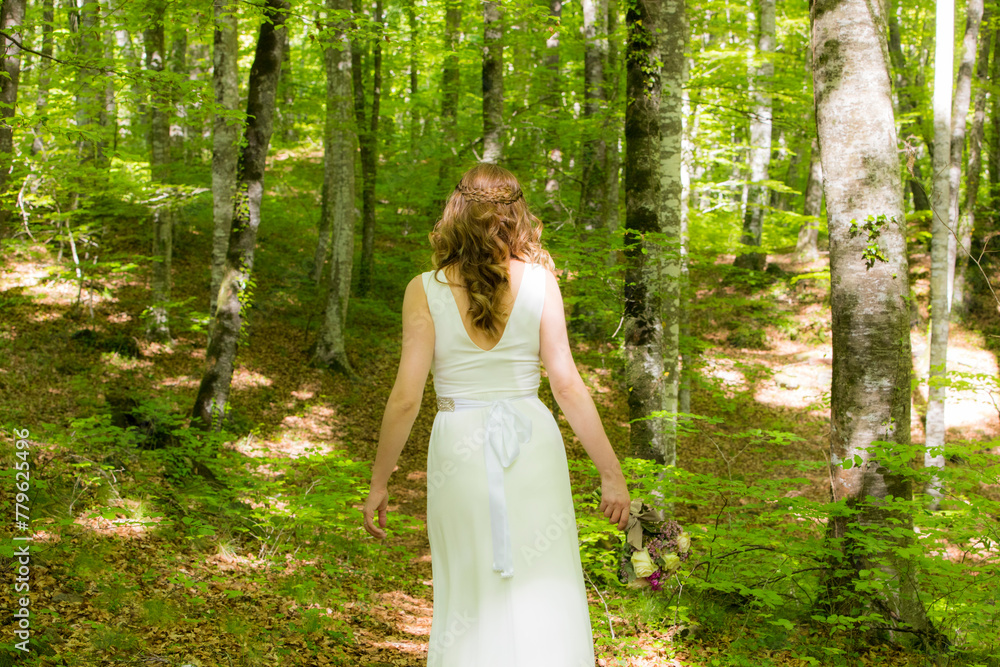 Bride in white dress walking through the spring forest in La Fageda d en Jorda, La Garrotxa, Spain Bride in white dress walking through the spring forest in La Fageda d en Jorda, La Garrotxa, Spain
