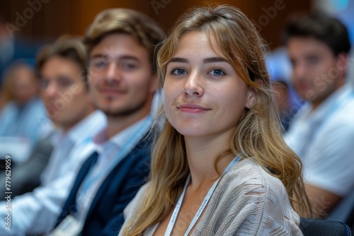 A young woman with blonde hair, focusing attentively at a seminar.