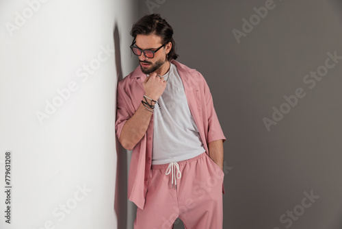 cool casual man with sunglasses holding hand in pocket and looking down