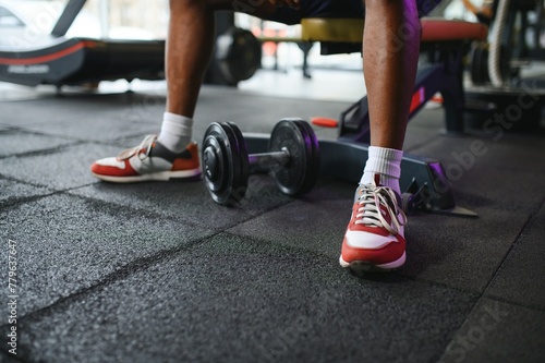 Young man strengthening biceps with dumbbell in gym