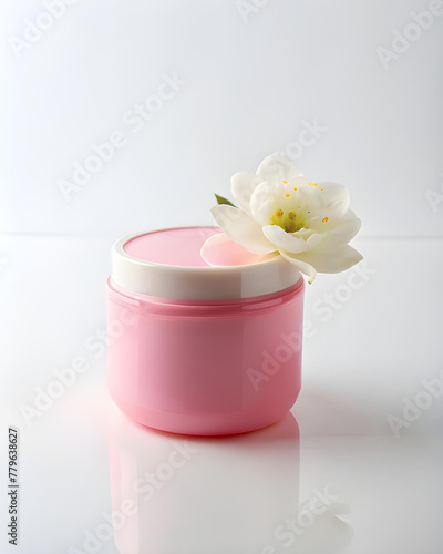 Pink plastic jar with cream and delicate flower  isolated on a blue background.