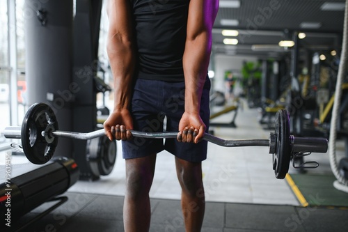 Athletic black guy making weightlifting or powerlifting at modern gym