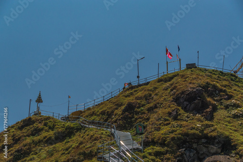 A hill with a white statue on top and a flag flying in the background
