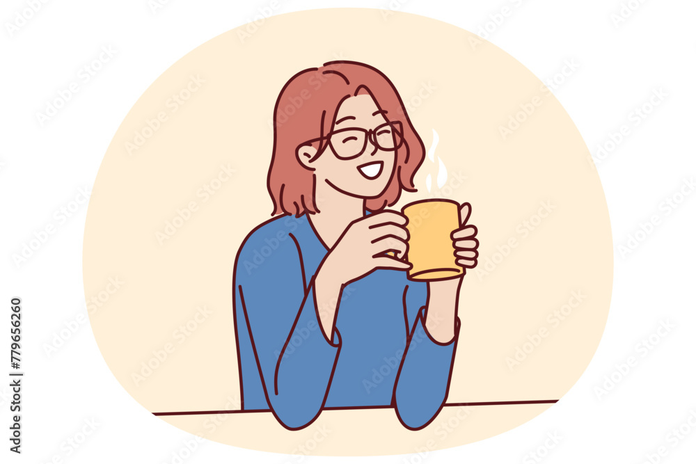 Joyful woman holding coffee mug sitting at table and smiling remembering happy moments from life during lunch break. Girl in casual clothes drinks hot tea or coffee to gain vigor and energy - obrazy, fototapety, plakaty 