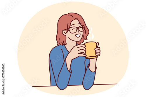 Joyful woman holding coffee mug sitting at table and smiling remembering happy moments from life during lunch break. Girl in casual clothes drinks hot tea or coffee to gain vigor and energy © drawlab19