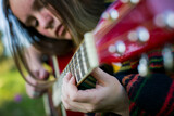 Close-up of a young woman's hands strumming the guitar.