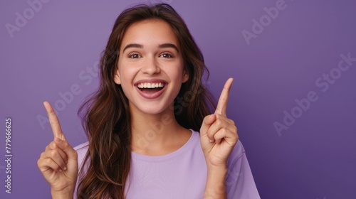 Portrait of a beautiful and cheerful young american woman smiling and pointing up with her fingers isolated on purple background  template for advertising or promotion  with copy space for text