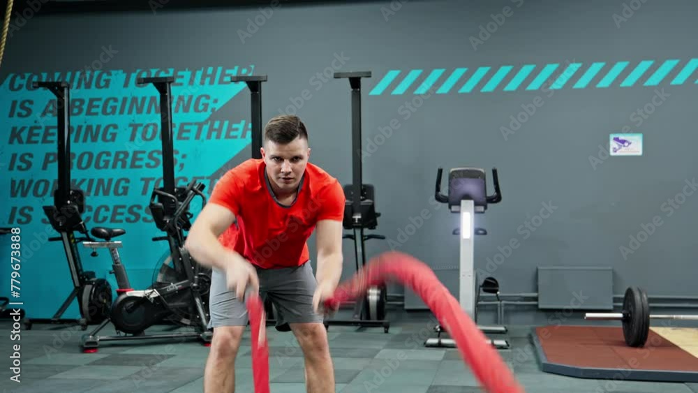 Male athlete exercises with battle ropes. Fit young man doing crossfit exercise with hitting the ropes. Cardio workout in gym. Physical activity indoors. Fitness concept. 4K, UHD Male athlete exercises with battle ropes. Fit young man doing crossfit exercise with hitting the ropes. Cardio workout in gym. Physical activity indoors. Fitness concept. 4K, UHD