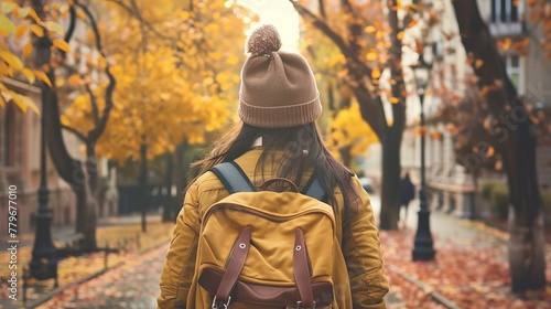 Rear view of teenage student girl walking in city during autumn