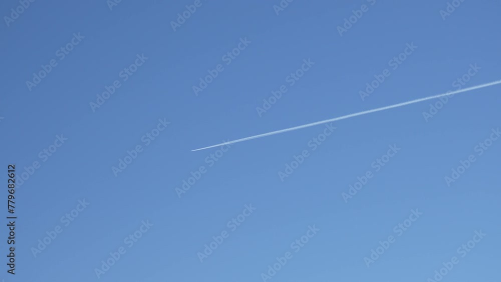 Distant jet plane flying on high altitude on clear blue sky with white trace of contrail Distant jet plane flying on high altitude on clear blue sky with white trace of contrail