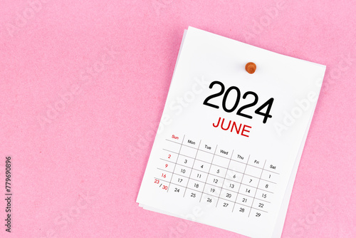 June 2024 calendar page and wooden push pin on pink background.
