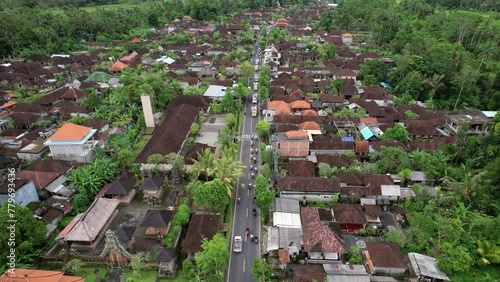 Aerial view of village street, motorbikes and trucks full of people in white ride behind procession. Celebration of Melis day at Bali, unusual traffic on the road at big religious event photo