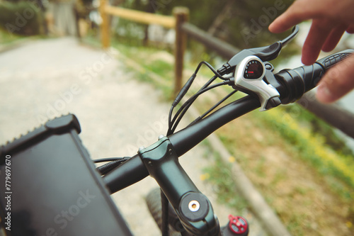 Close-up hand of a man adjusting the bicycle brakes while cycling in the mountains. Man in electric bike, gently squeezing hand brakes while descending during his ride in the mountains outdoors