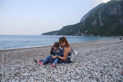 Woman and kid looking for rocks in pebble beach © Olga Bugro