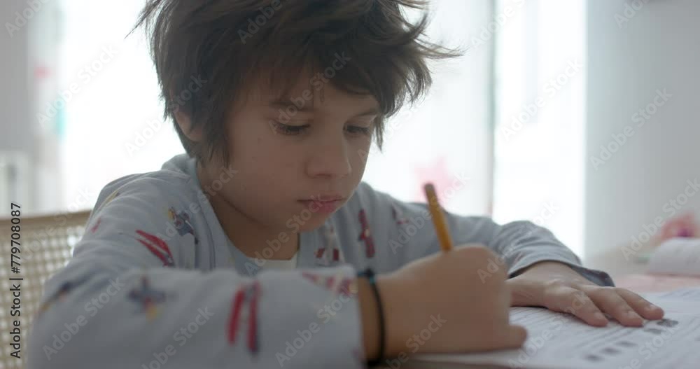 Young boy intently writing homework at a bright home desk during daytime Young boy intently writing homework at a bright home desk during daytime