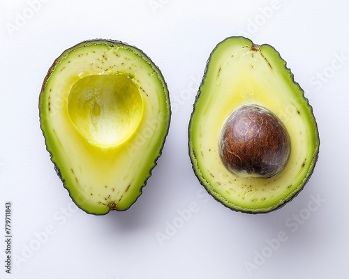 Ripe avocado, cut in half with the pit visible, on white