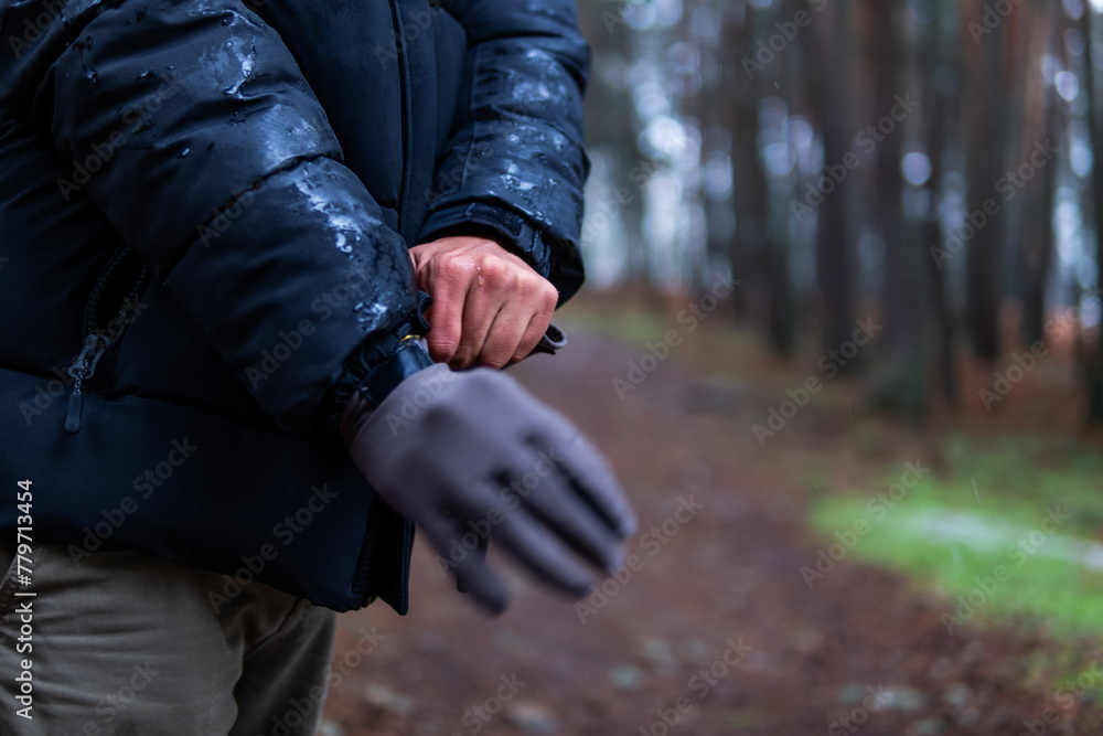 Unrecognizable hands donning snow and mountain gloves, amidst blurred forest backdrop, eco-tourism Unrecognizable hands donning snow and mountain gloves, amidst blurred forest backdrop, eco-tourism