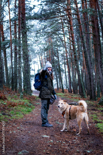 Woman with brown hair, embracing snowy wilderness with her dog, advocating sustainability in Ávila.