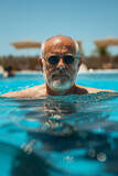 Senior man swimming in an outdoor pool.