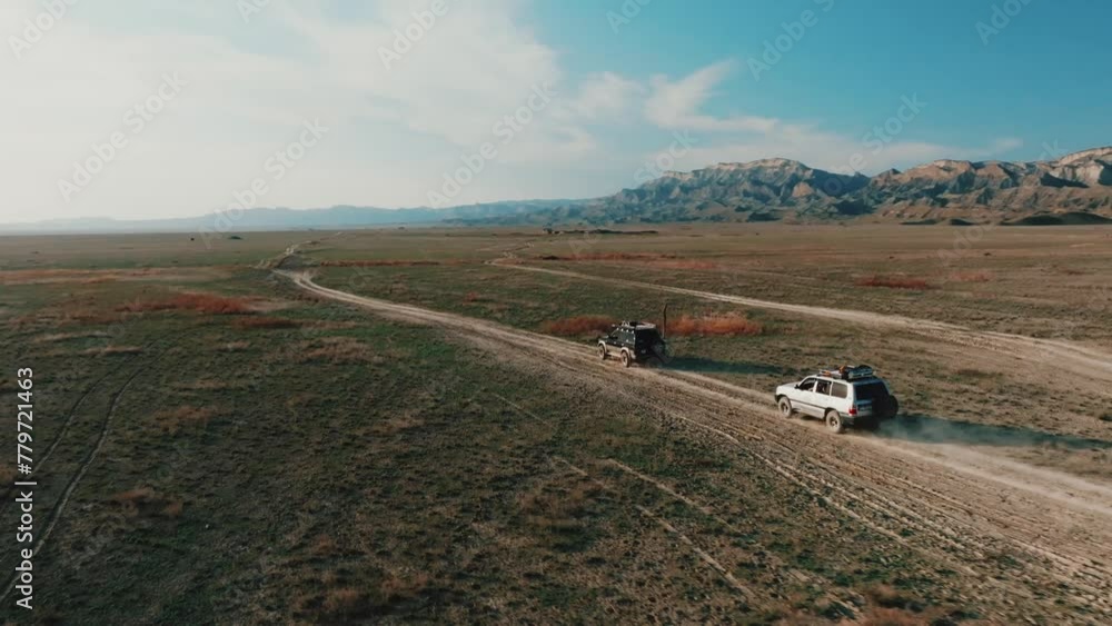 Drone tracking of a cars driving in the Vashlovani desert at the sunset . Drone tracking of a cars driving in the Vashlovani desert at the sunset .