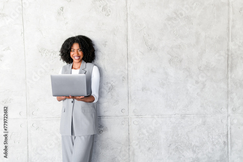 With a laptop in hand, the African-American businesswoman exudes a casual yet professional vibe, showcasing a balance between comfort and corporate expectations.