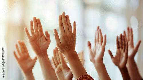 group of diverse hands raised up against light blurred background