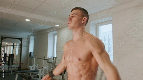 Young handsome man in black shorts recovers his breath after exercise in gym. Slow motion. Regular exercise as way of life photo