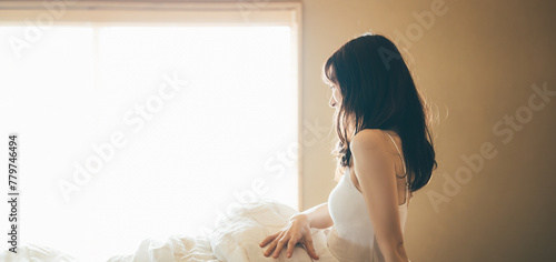 朝日が差し込むベッドルームで目覚める女性