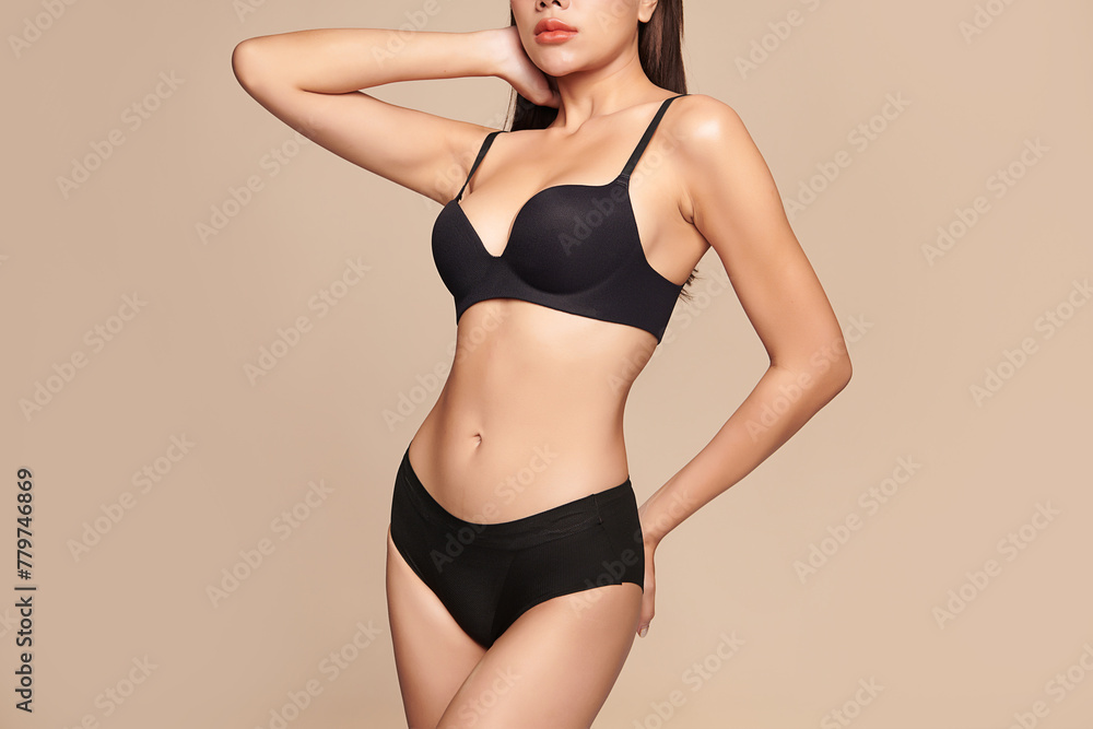 Naklejka premium Confident beautiful young asian woman posing in black lingerie on beige background, Perfect body,