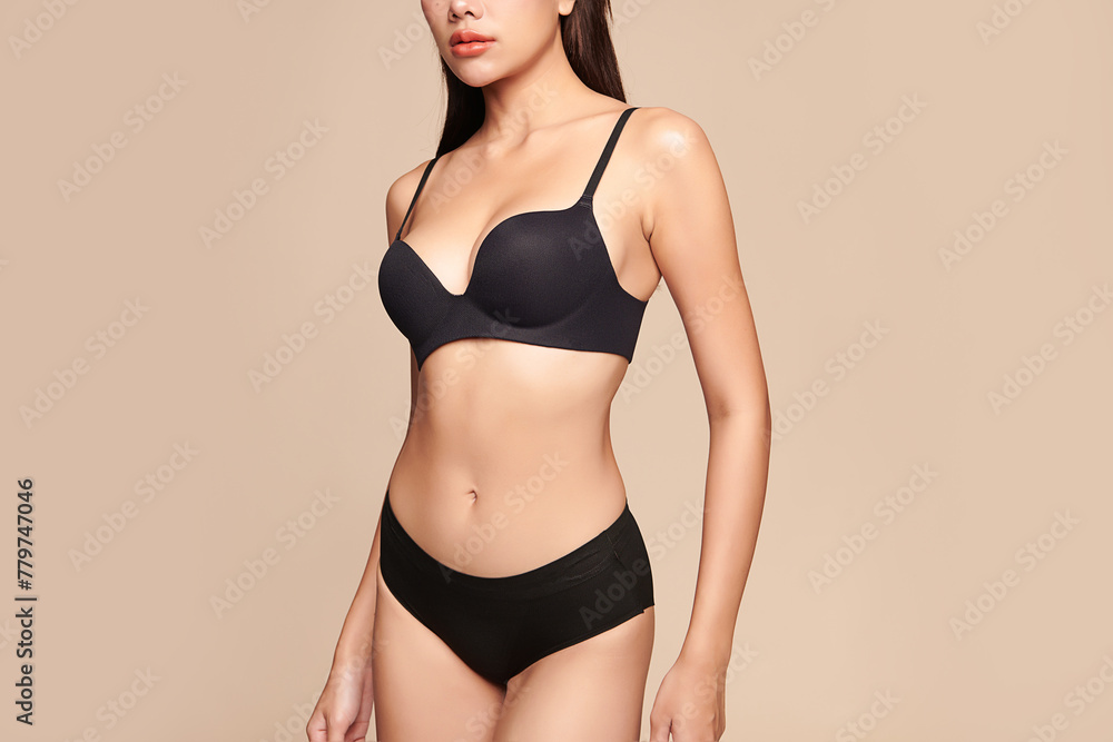 Fototapeta premium Confident beautiful young asian woman posing in black lingerie on beige background, Perfect body,