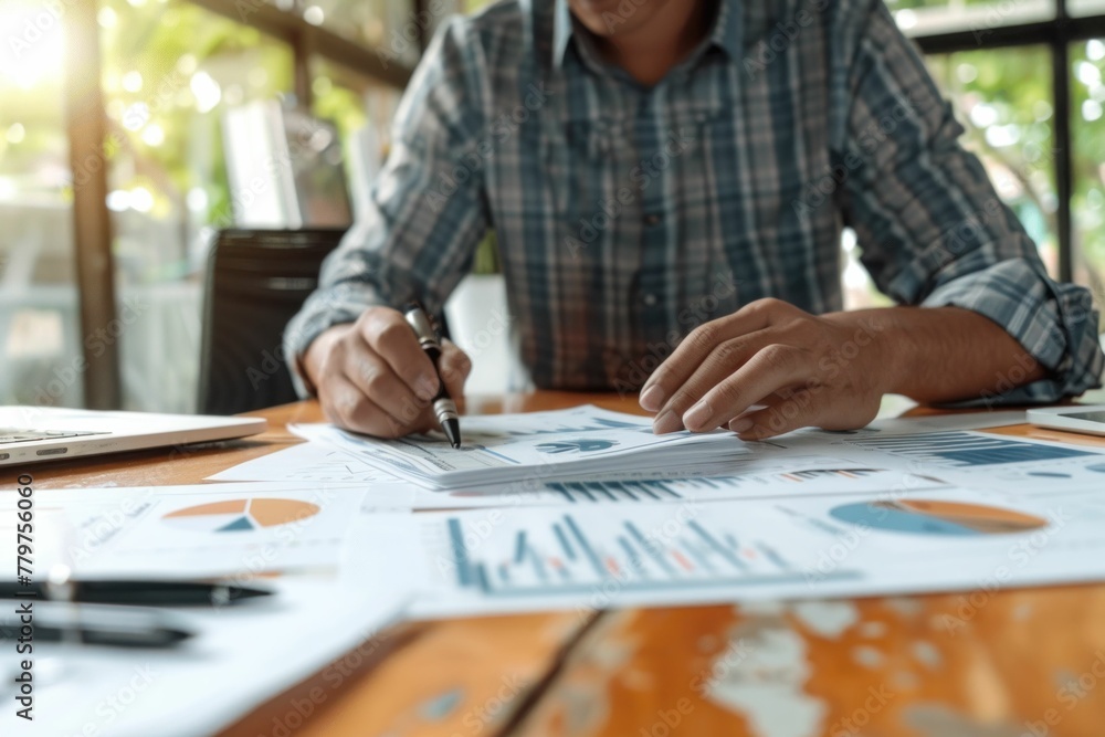 Busy businessman analyzing financial documents with laptop and pen at office desk, productivity concept Busy businessman analyzing financial documents with laptop and pen at office desk, productivity concept
