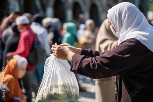 A woman in a hijab and a mask holds out a bag of food on the street to the needy. Charitable food distribution in Muslim countries