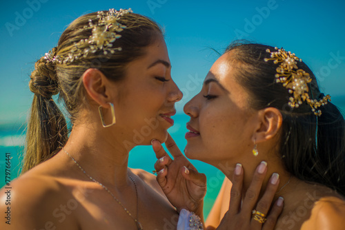 mujeres jóvenes latinas mirándose frente a frente mientras tienen sus manos en el rostro  photo