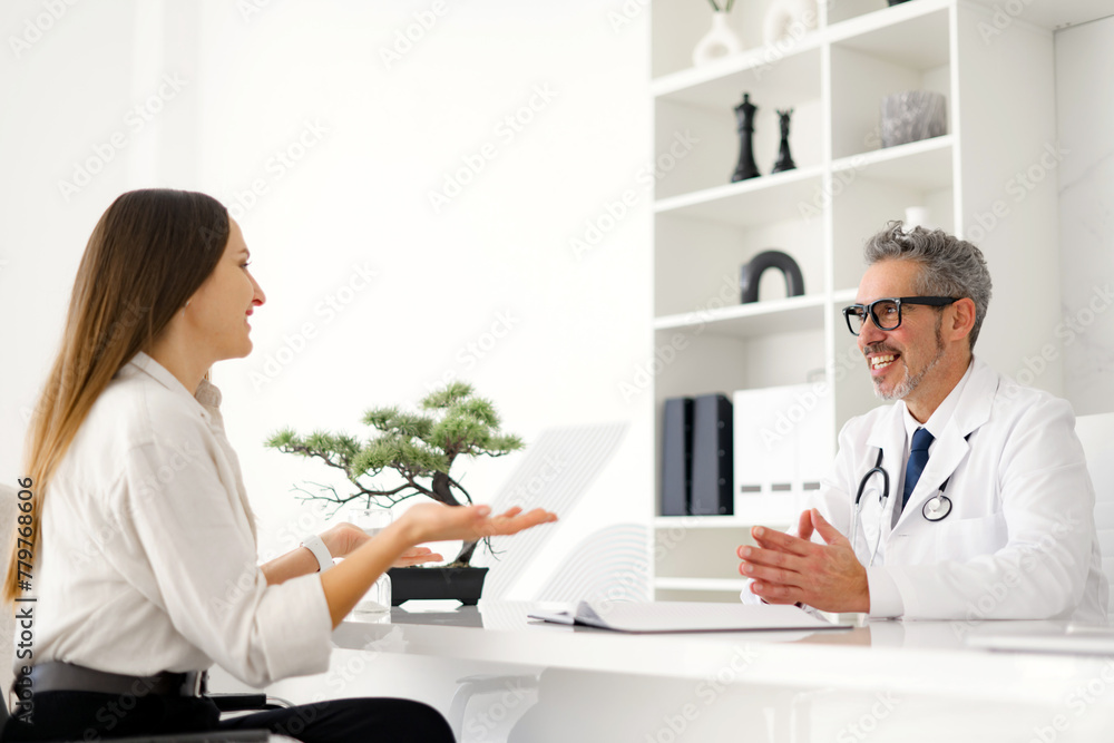 A senior doctor and a female patient discussing together during a medical consultation in a clinic. The image exudes warmth and comfort, the importance of good rapport in patient-doctor relationships. A senior doctor and a female patient discussing together during a medical consultation in a clinic. The image exudes warmth and comfort, the importance of good rapport in patient-doctor relationships.