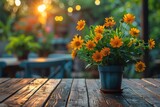 Vibrant yellow flowers in a blue pot rest on a rustic wooden table with a cozy outdoor cafe ambiance and soft sunlight