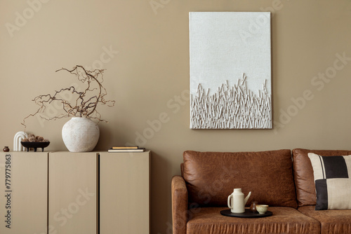 Aesthetic composition of cozy living room interior with mock up poster frame, brown sofa, patterned pillow, beige pitcher, vase with branch and personal accessories. Home decor. Template. © FollowTheFlow