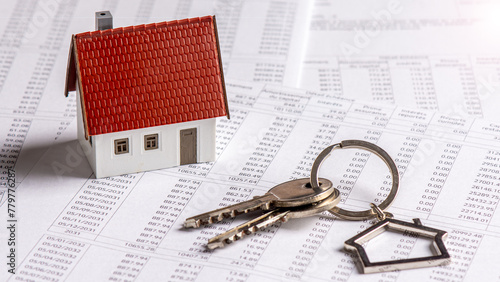 Trousseau de clés et maquette de maison individuelle posés sur un document bancaire d'échéancier de prêt immobilier. Concept d'achat immobilier à crédit, de durée et de taux d'intérêt d'emprunt photo