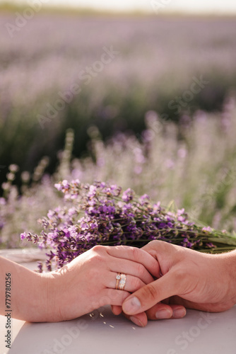 Lovely couple on the lavender field, holding hands. A man and a woman are hold hands in a lavender field. Engagement closeup.