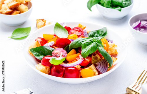 Summer italian salad with stale bread, tomatoes, red onion, olive oil, salt and green basil, white table background, top view