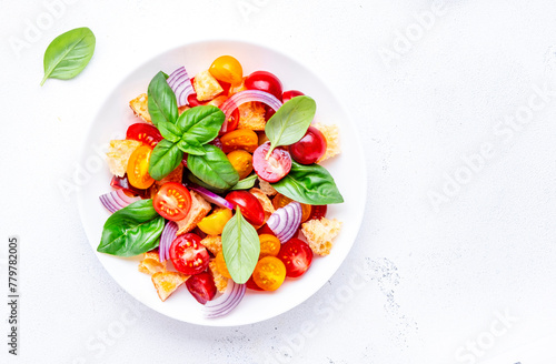 Summer italian salad with stale bread, tomatoes, red onion, olive oil, salt and green basil, white table background, top view