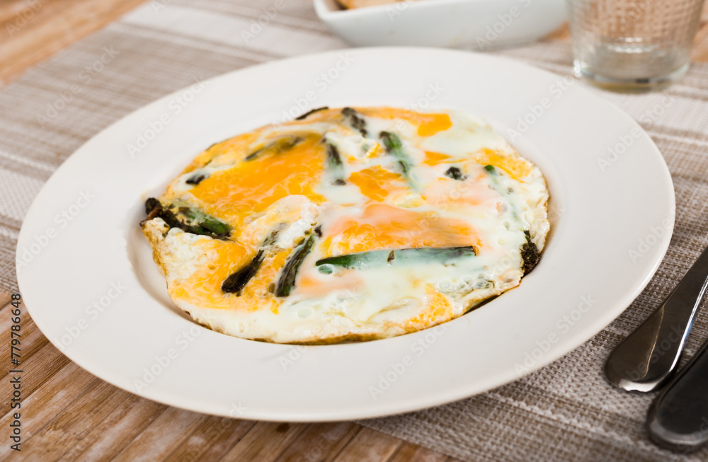 Closeup of fried eggs with asparagus at plate