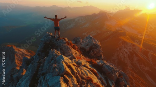 Person with open arms on a mountain peak at sunrise or sunset © Natalia