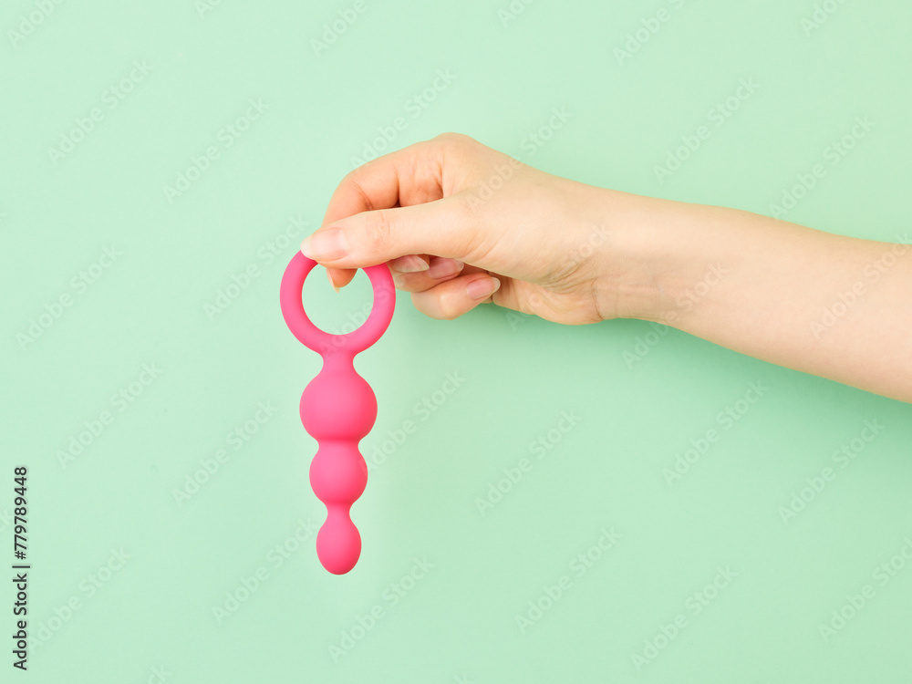 Fototapeta premium Woman's hand holding adult sex toy over mint background