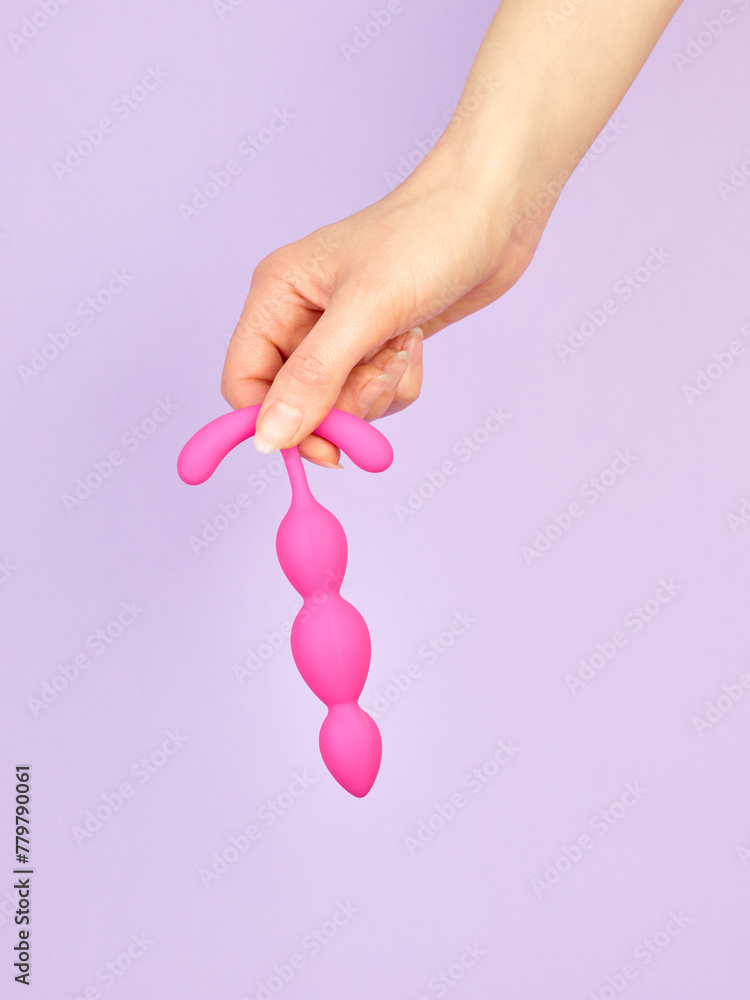 Fototapeta premium Woman's hand holding adult sex toy over violet background