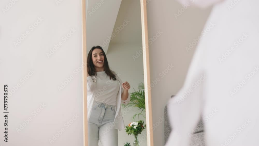 An exuberant brunette woman is captured dancing joyfully in front of a mirror, embodying happiness and a vibrant energy. An exuberant brunette woman is captured dancing joyfully in front of a mirror, embodying happiness and a vibrant energy.