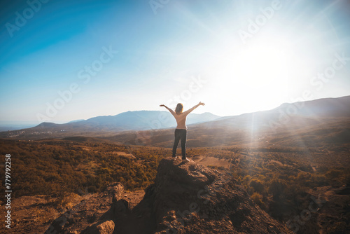 The girl looks at the mountains while facing the sun. High quality photo