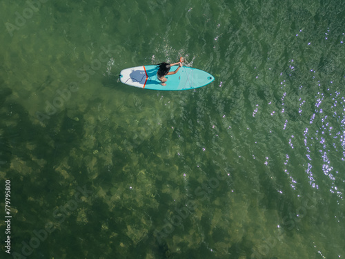 cenital copyspace above view Young Latin paddleboarding with board in the sea on a sunny summer day © EDER