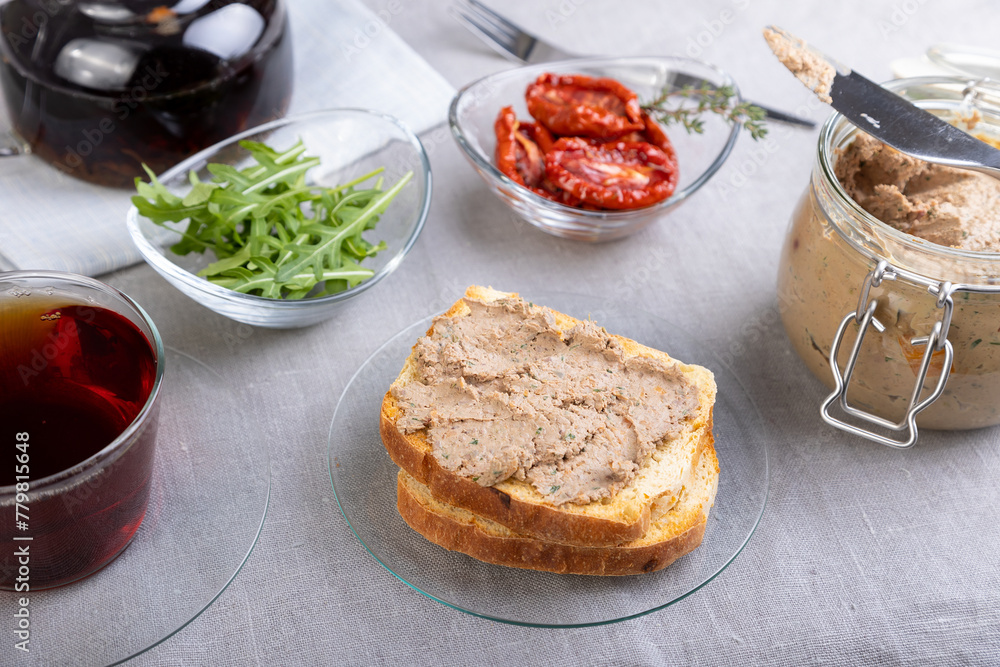 Chicken liver pate with wheat bread, arugula, sun-dried tomatoes and black tea. Homemade traditional rustic cuisine. Breakfast or snack option. Selective focus, close-up. Chicken liver pate with wheat bread, arugula, sun-dried tomatoes and black tea. Homemade traditional rustic cuisine. Breakfast or snack option. Selective focus, close-up.