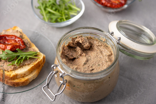 Chicken liver pate with wheat bread, arugula, sun-dried tomatoes and black tea. Homemade traditional rustic cuisine. Breakfast or snack option. Selective focus, close-up.