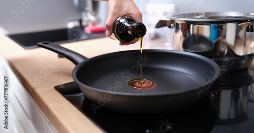 Chef pouring olive oil into frying pan in kitchen closeup. Healthy eating concept photo